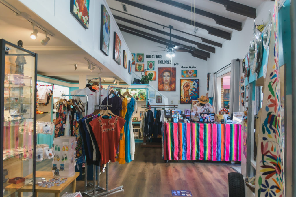 Photograph of the inside of Mercadito Monarca, showcasing colorful cultural clothes, jewelry, and art.