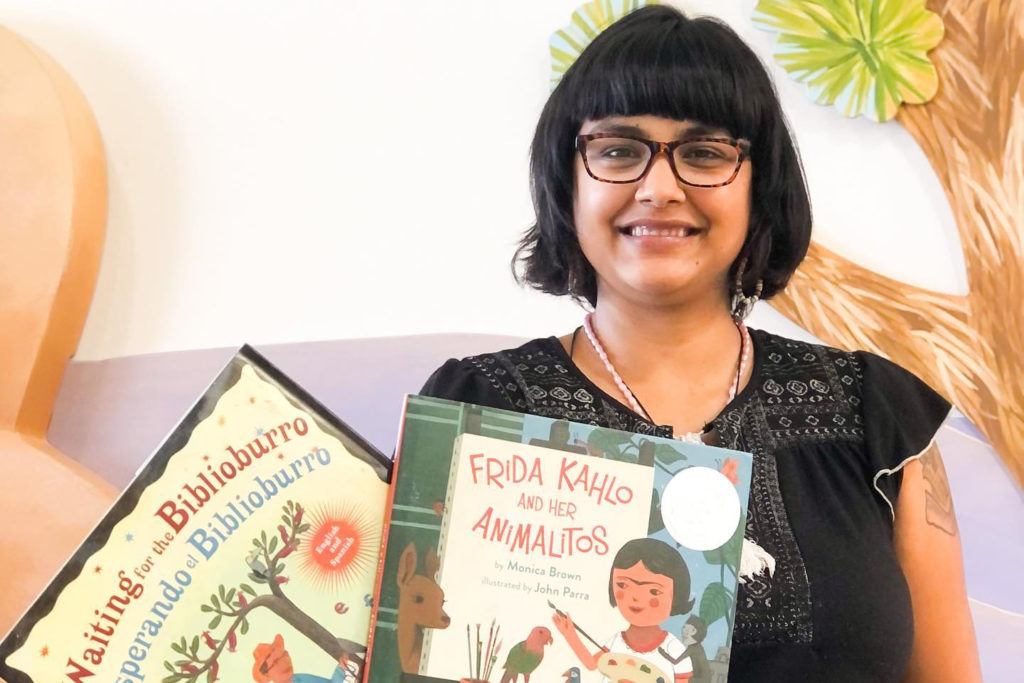 Southern California Children's Museum staff holding a book called "waiting for the Bilblioburro" and "Frida Kahlo and her Animalitos"