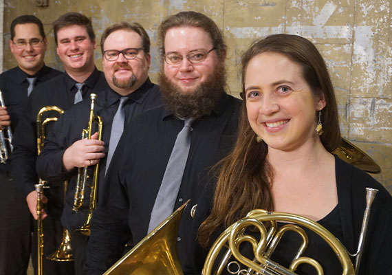 Photograph of Oakwood Brass Ensemble holding their instruments while dressed in all black.