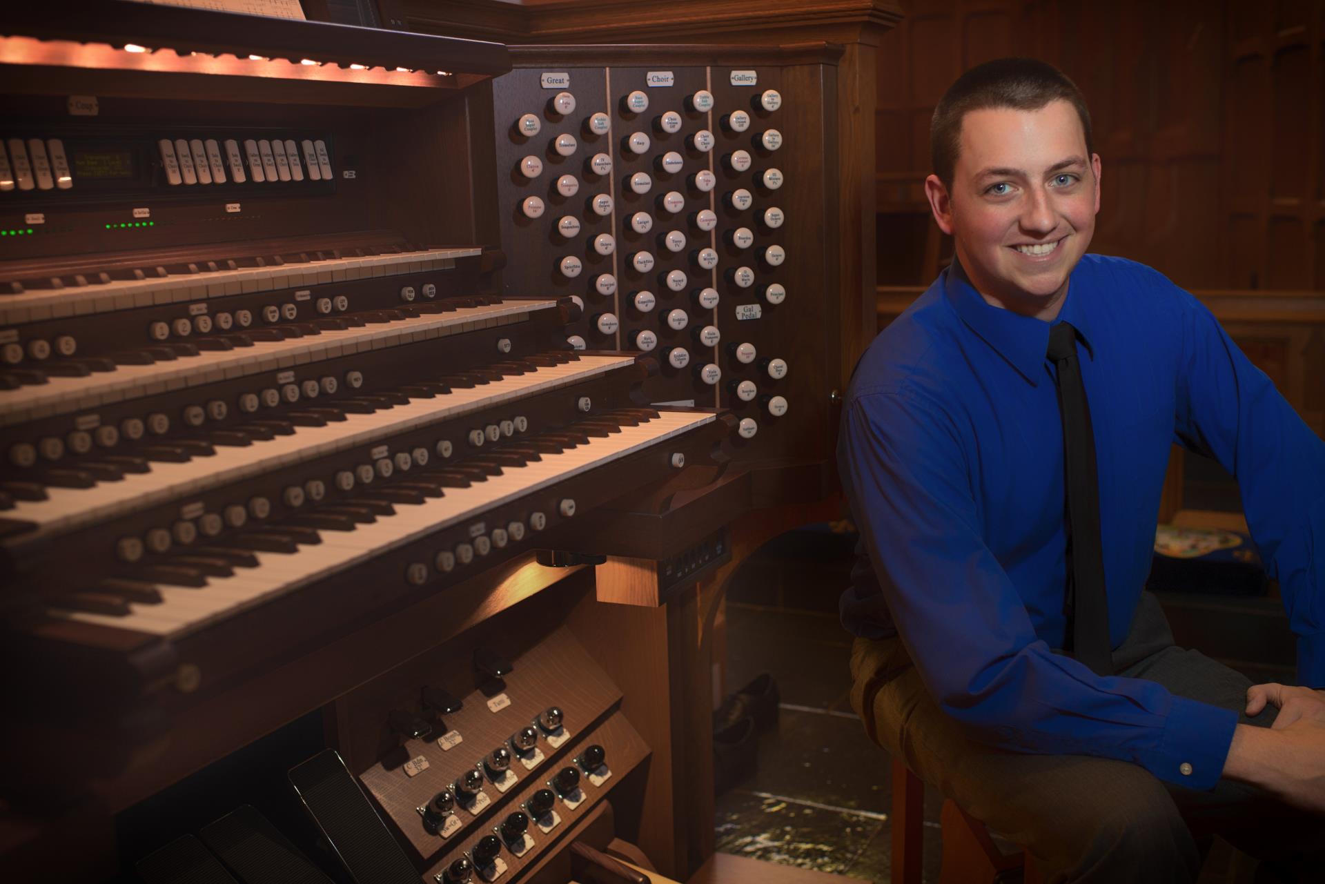 Organist Aaron Shows sits in front of an organ.