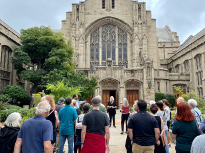 Group stands in front of First United Methodist Church in Playhouse Village as part of a walking tour.