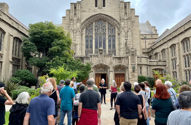 Group stands in front of First United Methodist Church in Playhouse Village as part of a walking tour.