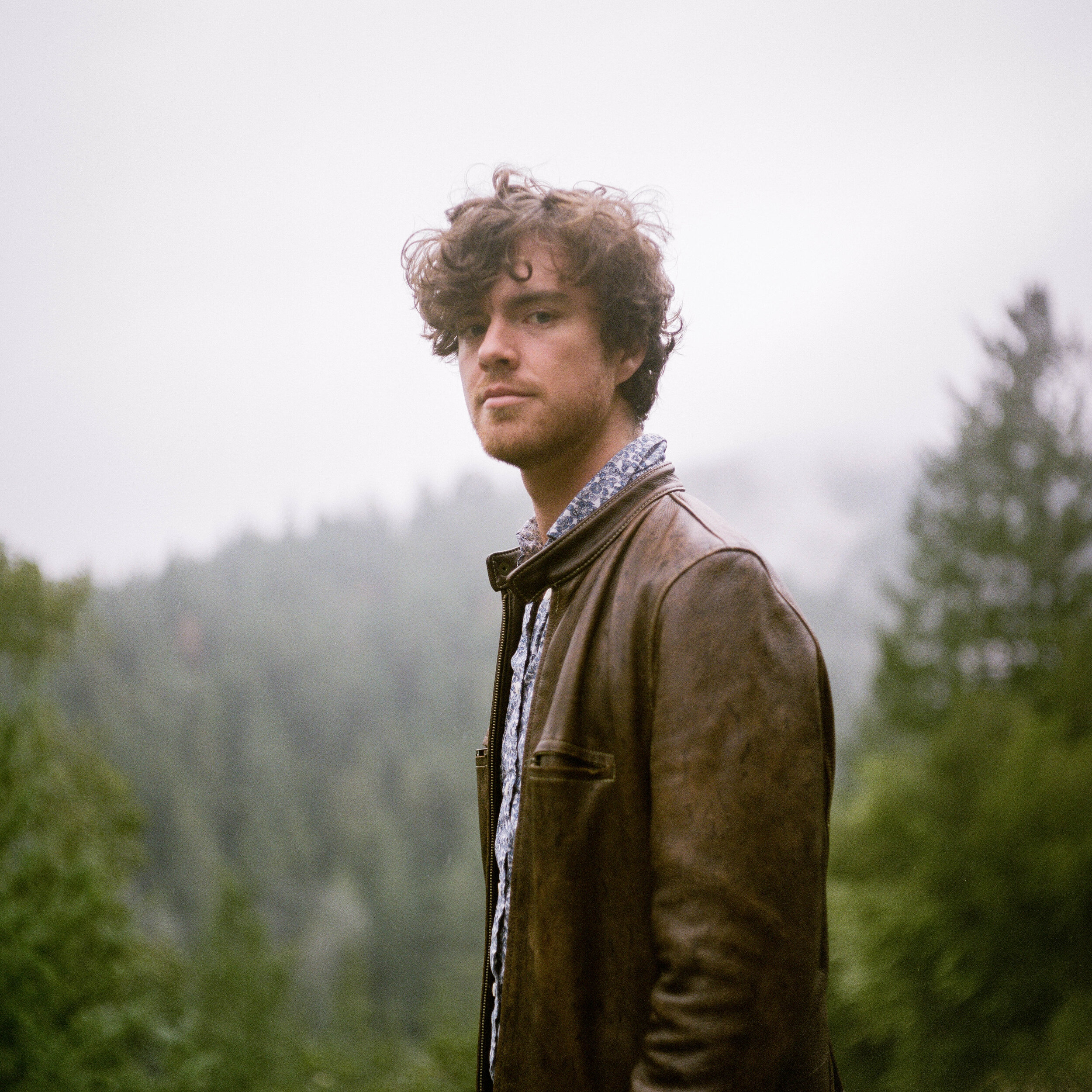 Pianist Ryan Whyman stands against a forest backdrop