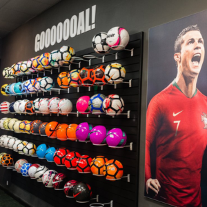Shelves in rows of soccer balls at Pro Soccer in Pasadena with the word Gooooooaaaal! across the top of the display.