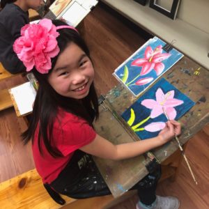 Young girl paints a pink lily at Drawn2Art