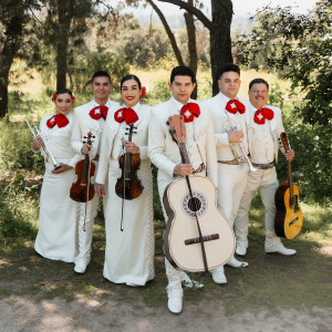 Mariachi Tierra Mia wears a white ensemble while posing with their instruments under a tree