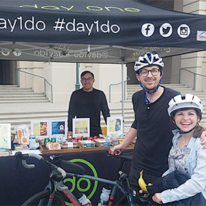 Two bicyclists stop by the Day One tent to pic up some goodies on Bike to Work Day.