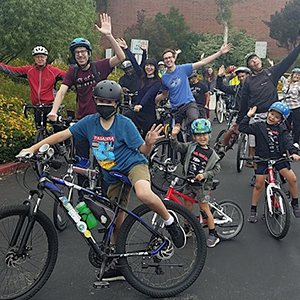 Group of riders of all ages pose on their bikes as they ready to start a ride for Bike Month.