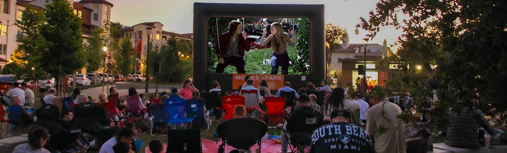 Attendees sit on lawn chairs and blankets ready to watch the featured film on a giant inflatable screen at Playhouse Village Park.