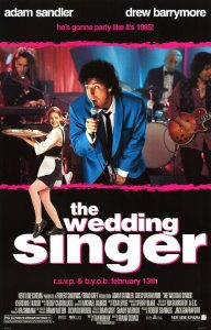 Poster for the movie "The Wedding Singer" featuring Adam Sandler singing into a microphone in a bright blue suit, with Drew Barrymore smiling while holding a tray of food in a waitress outfit. A band plays in the background with pink stage lighting. The tagline at the top reads “He's gonna party like it's 1985!” and the bottom text reads “the wedding singer” in bold white and pink letters.